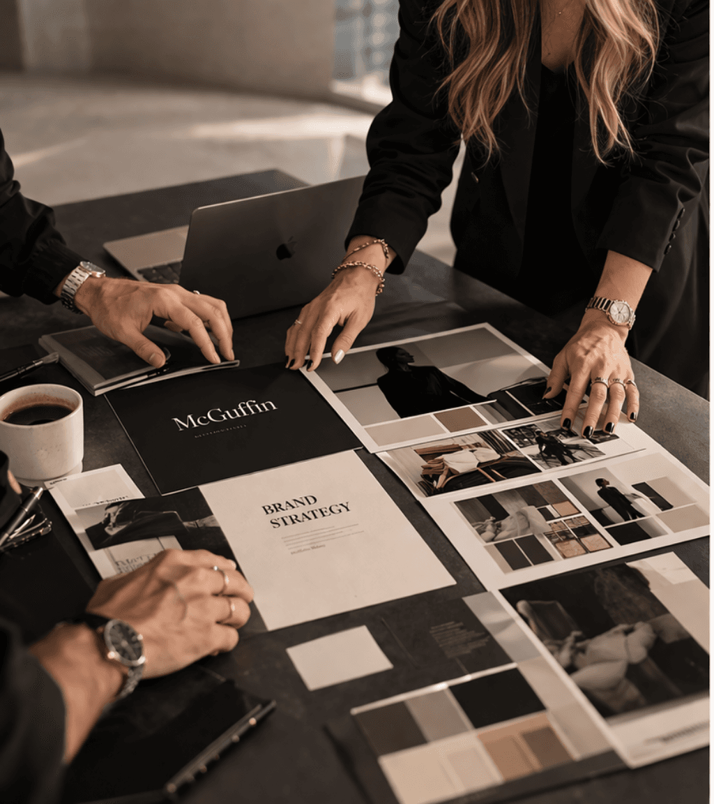 Professionisti che esaminano documenti di brand strategy e moodboard fotografici su un tavolo da lavoro.