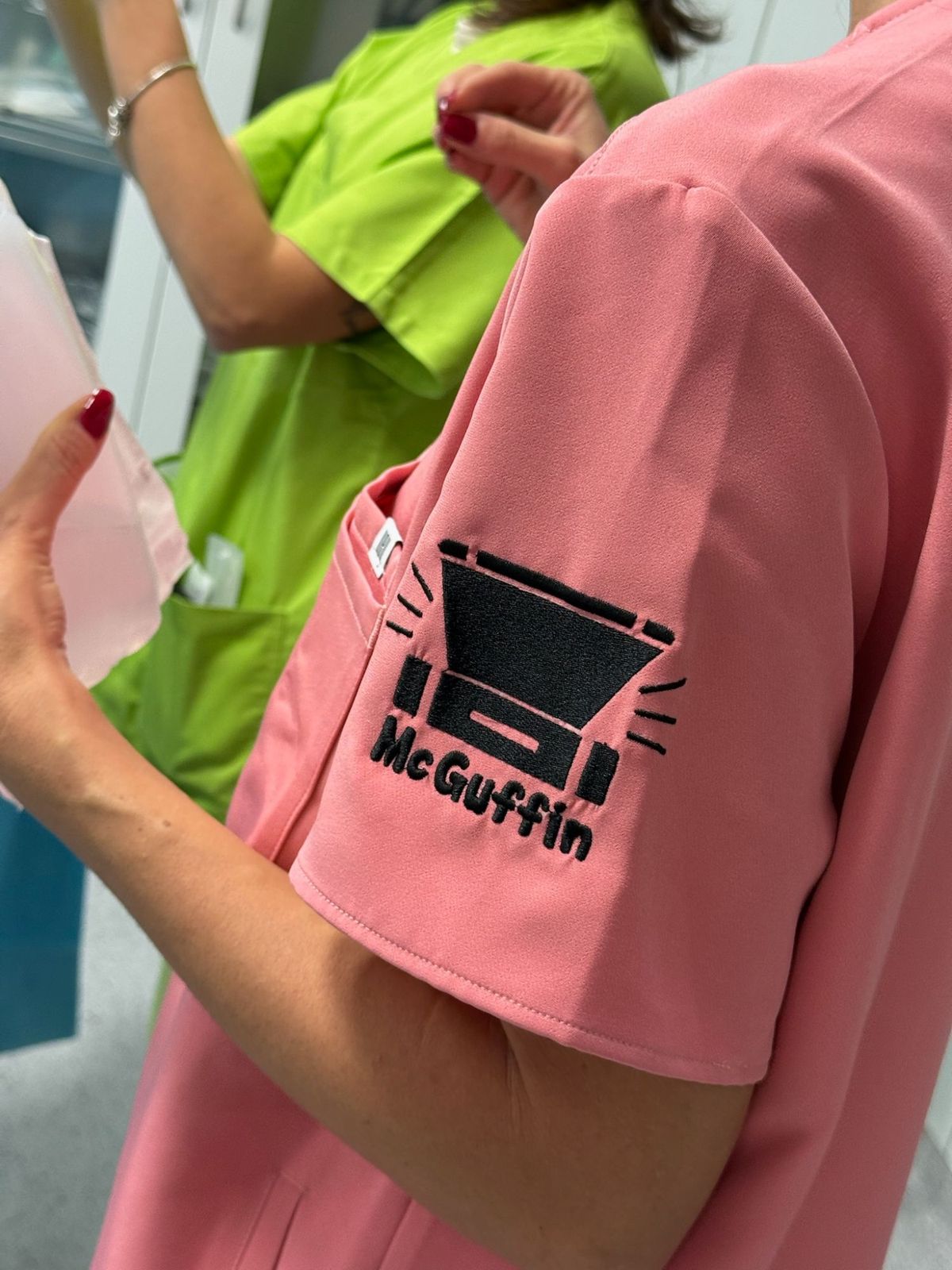 Logo McGuffin ricamato sulla manica di una divisa rosa.
