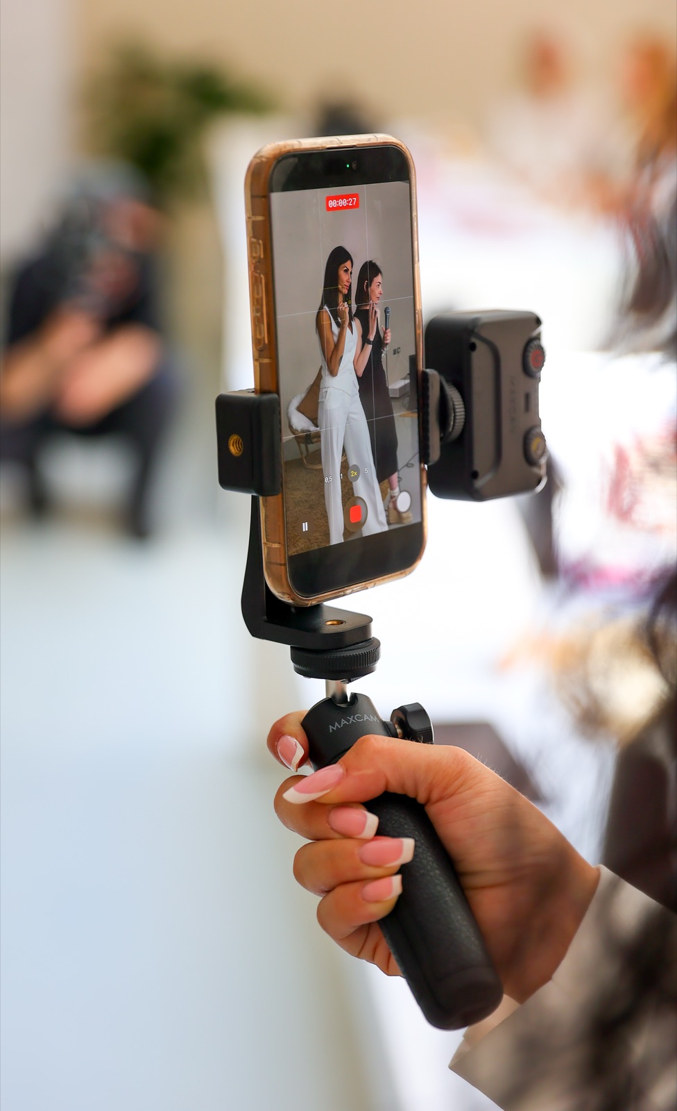 Smartphone su stabilizzatore che riprende due donne durante un evento.