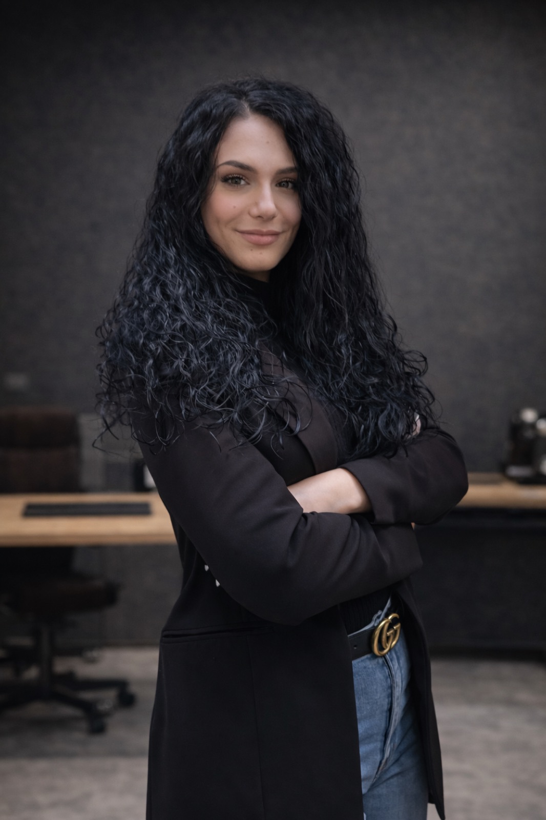 Giulia Imola in blazer nero, braccia incrociate, in ufficio.