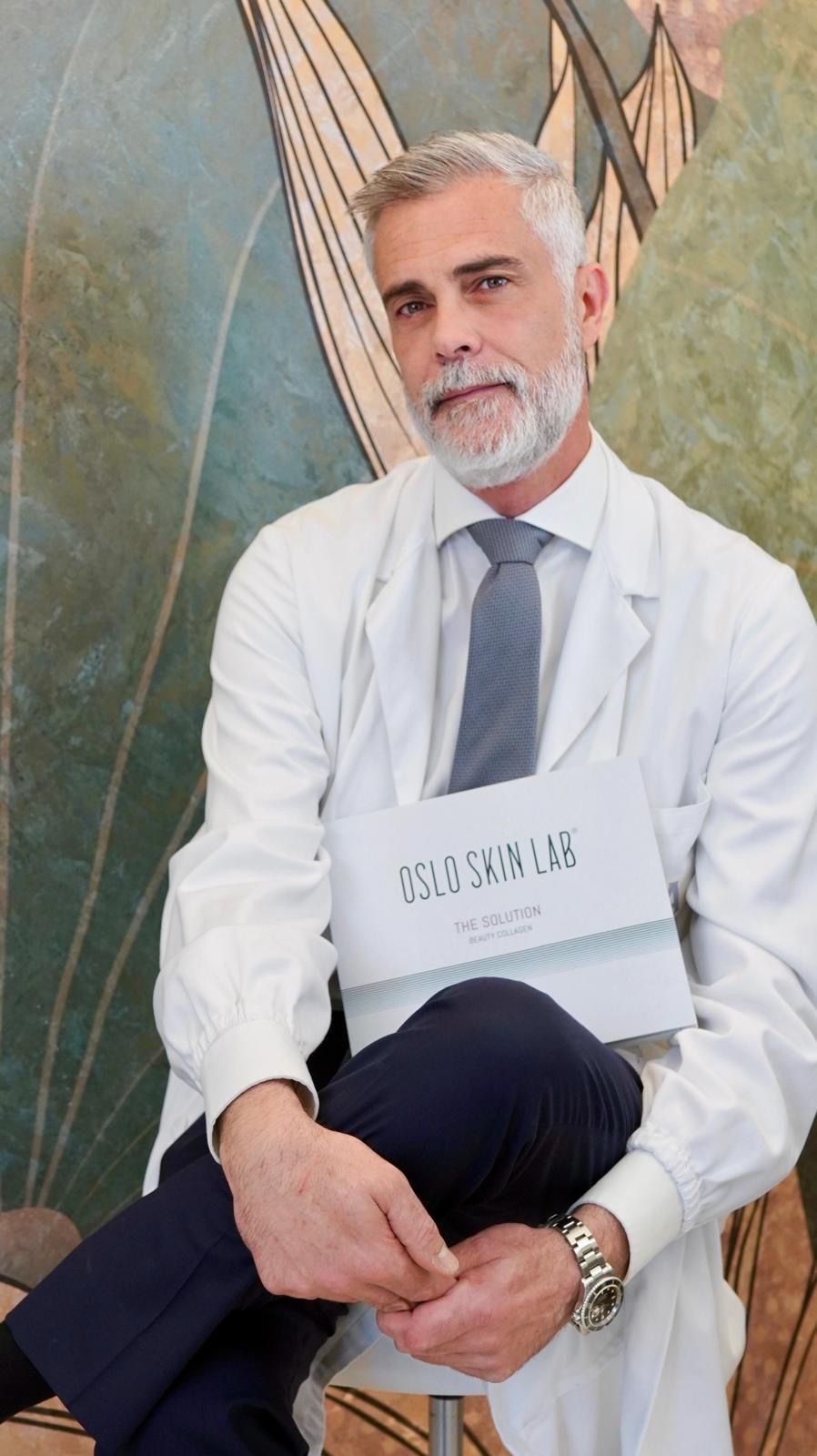 Medico in camice bianco con una confezione Oslo Skin Lab.
